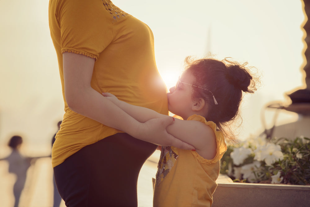 pregnant female and her daughter kissing her tammy , illustrating wellness after taking zenutri vitamins