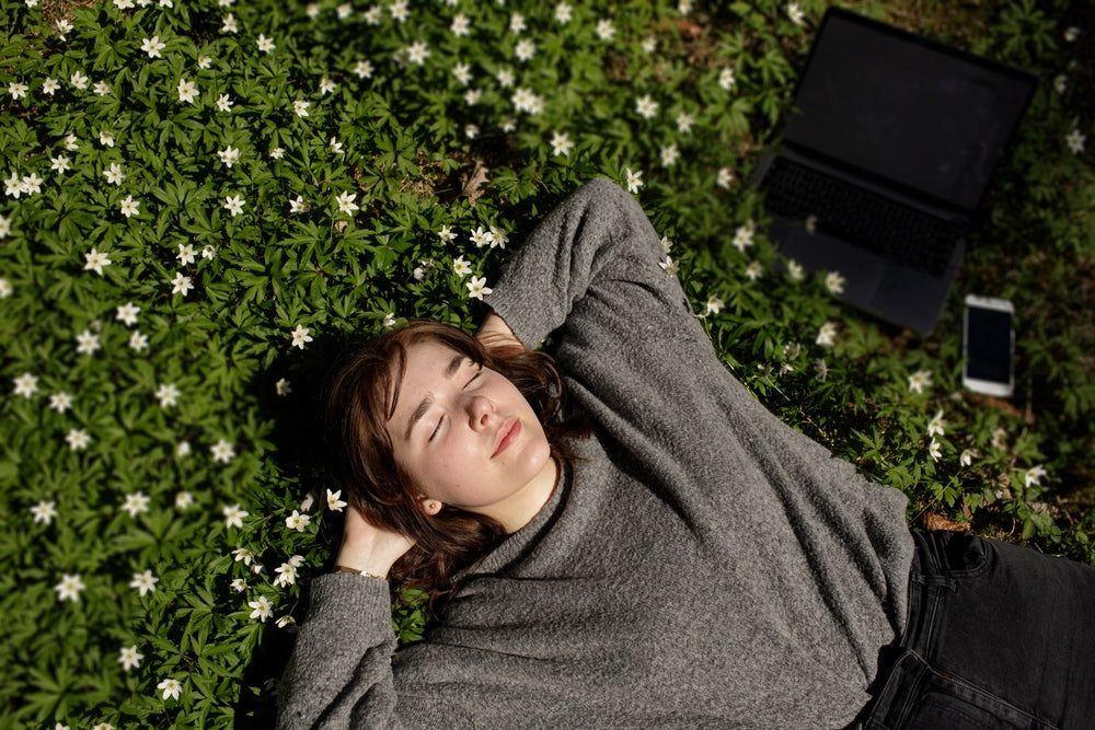 female laying down on the grass in the sun  illustrating wellness after  taking zenutri vitamin pill