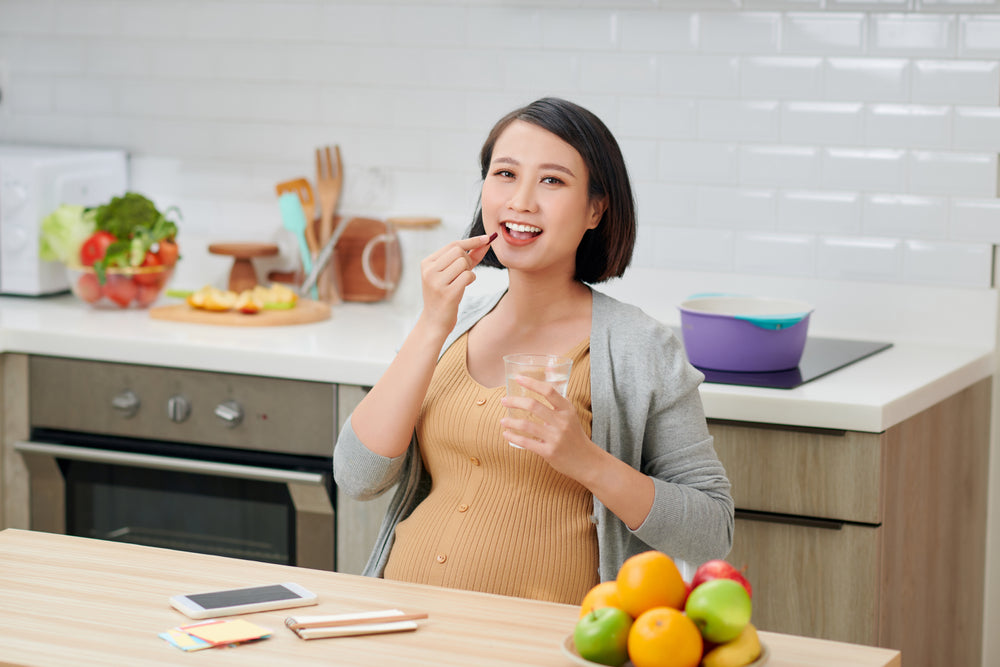 Pregnant women taking  zenutri vitamins  in her kitchen space